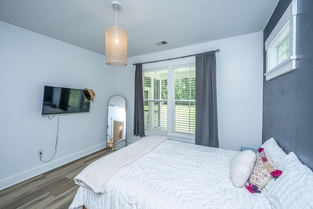 bedroom featuring wood finished floors, multiple windows, and baseboards
