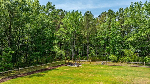 view of yard with a fire pit and a wooded view