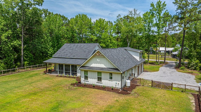 view of front facade with a sunroom, a shingled roof, an attached garage, driveway, and board and batten siding