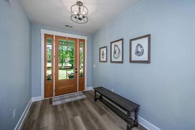 doorway to outside featuring a chandelier, dark wood-type flooring, and baseboards