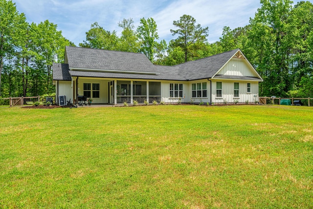 rear view of property featuring board and batten siding, roof with shingles, and a yard