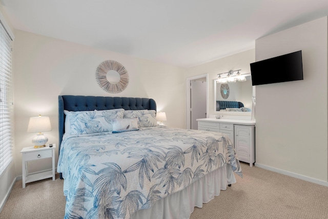 bedroom featuring connected bathroom and light colored carpet