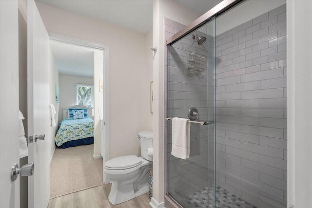 bathroom featuring toilet, wood-type flooring, and an enclosed shower