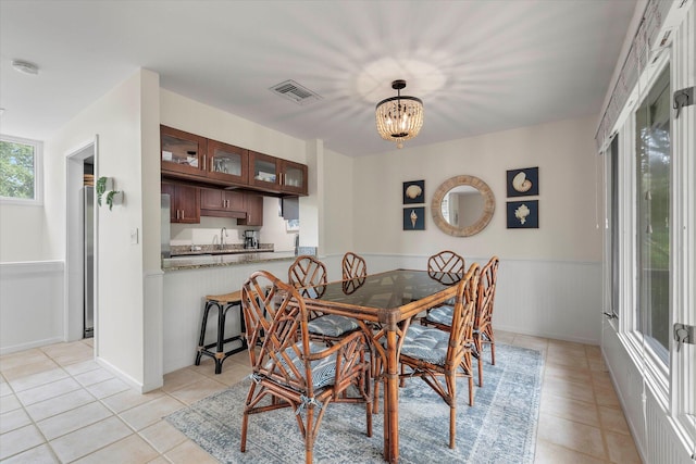 tiled dining space featuring sink and a chandelier