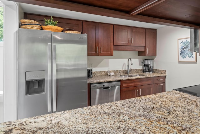 kitchen featuring appliances with stainless steel finishes, sink, and light stone countertops