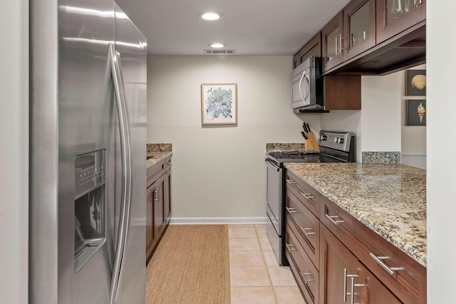 kitchen with appliances with stainless steel finishes, light stone counters, and light tile patterned floors