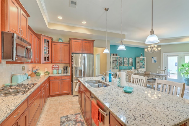 269 Village Stone Cir, Summerville, SC 29483 - kitchen featuring stainless steel appliances, a tray ceiling, brown cabinetry, backsplash, and decorative light fixtures