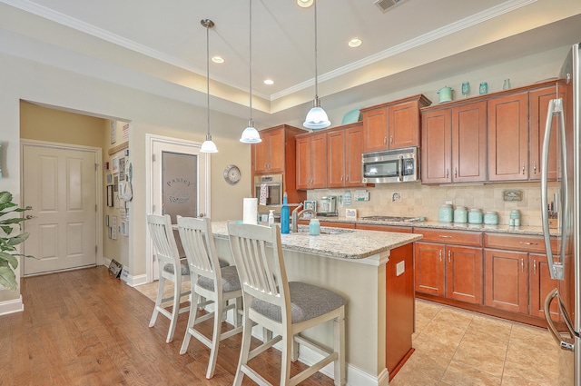 269 Village Stone Cir, Summerville, SC 29483 - kitchen with appliances with stainless steel finishes, backsplash, brown cabinetry, a kitchen breakfast bar, and light stone counters