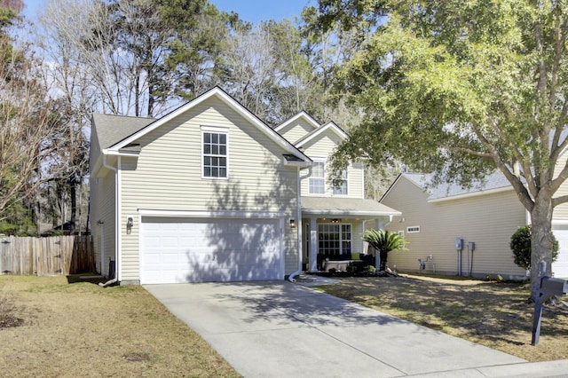 traditional home featuring a front lawn, concrete driveway, a garage, and fence