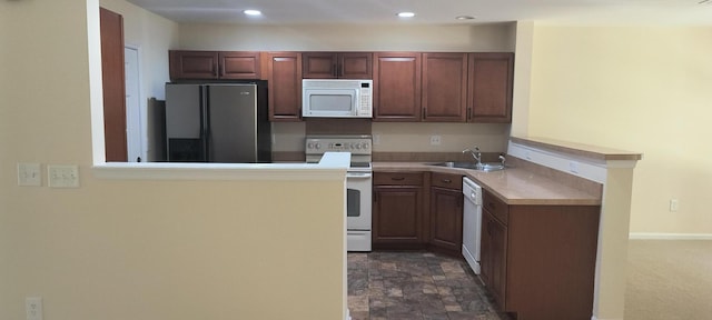 kitchen with white appliances, kitchen peninsula, and sink