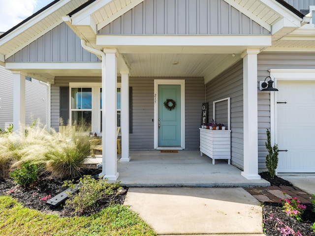 view of exterior entry featuring a porch and a garage