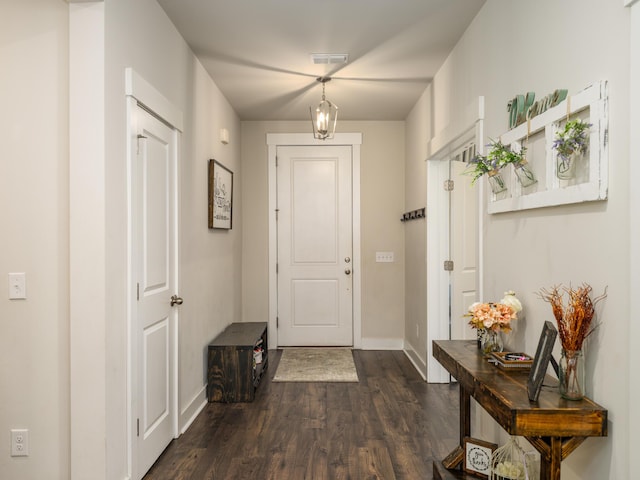 doorway with dark hardwood / wood-style flooring and an inviting chandelier