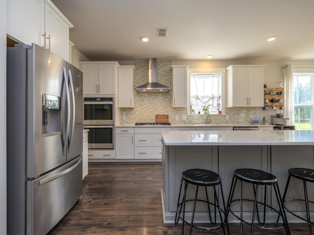 kitchen featuring white cabinets, appliances with stainless steel finishes, dark hardwood / wood-style flooring, and wall chimney range hood