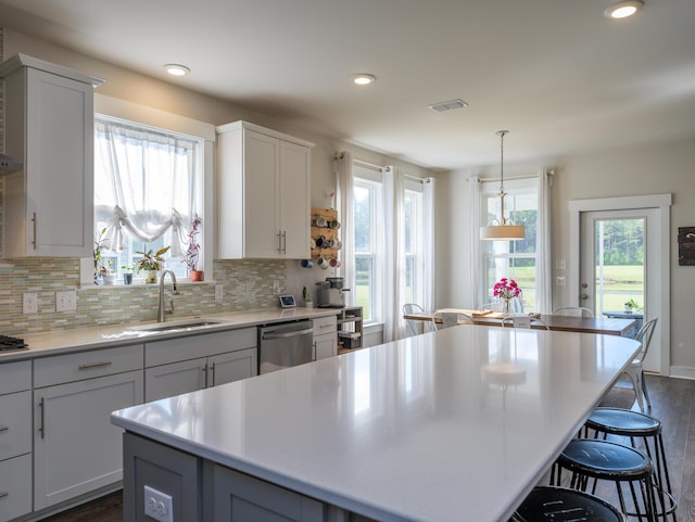 kitchen featuring stainless steel dishwasher, a center island, dark hardwood / wood-style flooring, and white cabinetry