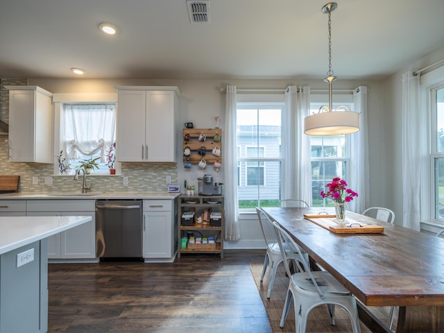 kitchen with dark hardwood / wood-style flooring, stainless steel dishwasher, sink, white cabinets, and hanging light fixtures