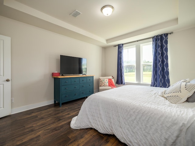 bedroom with dark hardwood / wood-style flooring and a tray ceiling