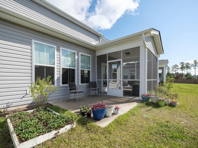 rear view of house featuring a sunroom, a patio area, and a lawn