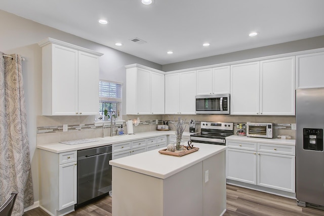 kitchen featuring white cabinets, backsplash, wood finished floors, visible vents, and appliances with stainless steel finishes