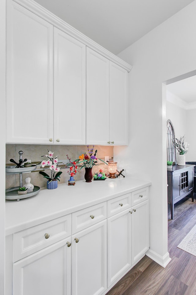 bar with baseboards, wood finished floors, and backsplash