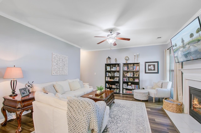 living room featuring crown molding, a ceiling fan, wood finished floors, and a tile fireplace