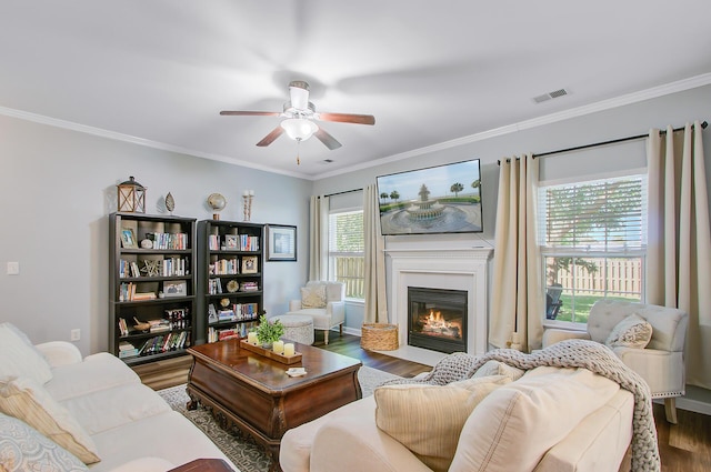 living room featuring ceiling fan, wood finished floors, visible vents, and ornamental molding