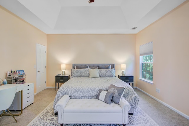 bedroom featuring visible vents, light carpet, baseboards, and a tray ceiling