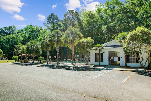uncovered parking lot with a community pool and fence