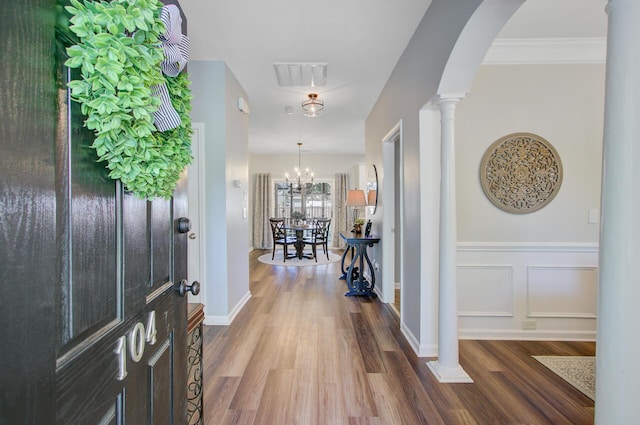 entrance foyer featuring arched walkways, wood finished floors, visible vents, and ornate columns