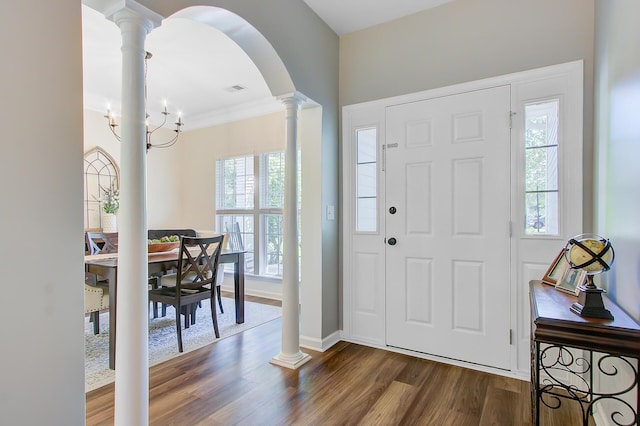 foyer with arched walkways, dark wood finished floors, a healthy amount of sunlight, and decorative columns