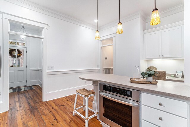 kitchen with stainless steel oven, dark hardwood / wood-style floors, crown molding, pendant lighting, and white cabinets