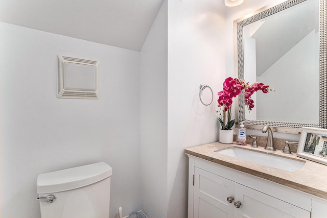 bathroom featuring vanity, toilet, and lofted ceiling