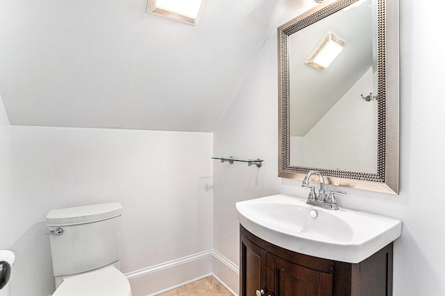 bathroom with toilet, vanity, and vaulted ceiling