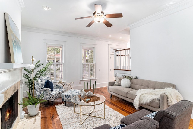 living room with a fireplace, light hardwood / wood-style floors, ceiling fan, and crown molding