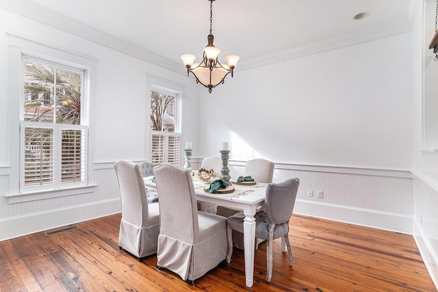 dining room with crown molding, a chandelier, and hardwood / wood-style flooring