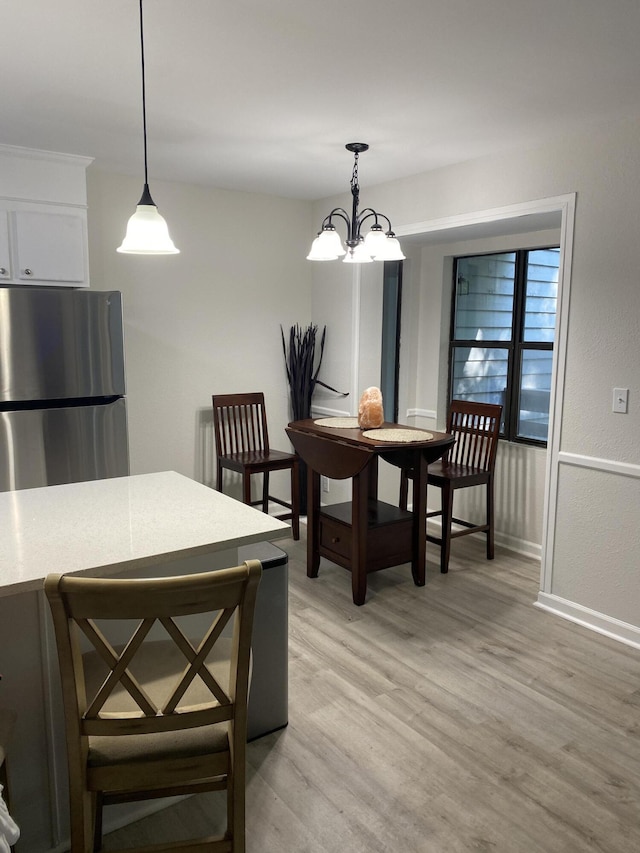 dining room with light hardwood / wood-style flooring and an inviting chandelier