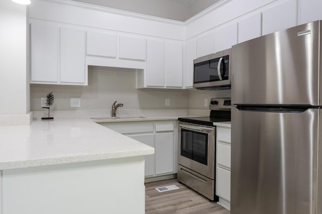 kitchen with white cabinetry, sink, light hardwood / wood-style floors, and appliances with stainless steel finishes