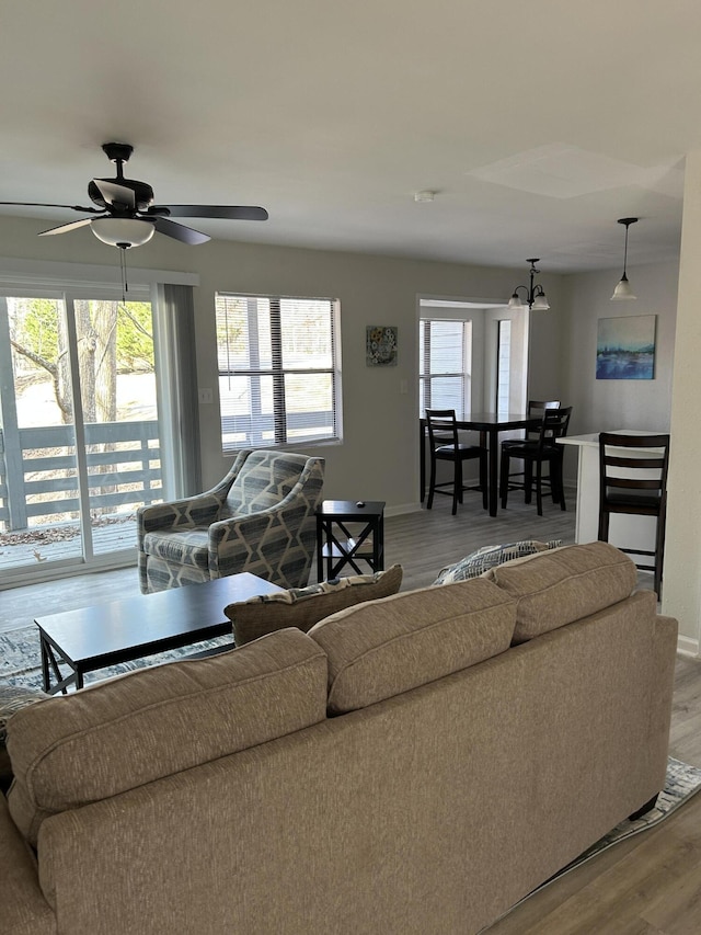 living room with light hardwood / wood-style flooring and ceiling fan with notable chandelier