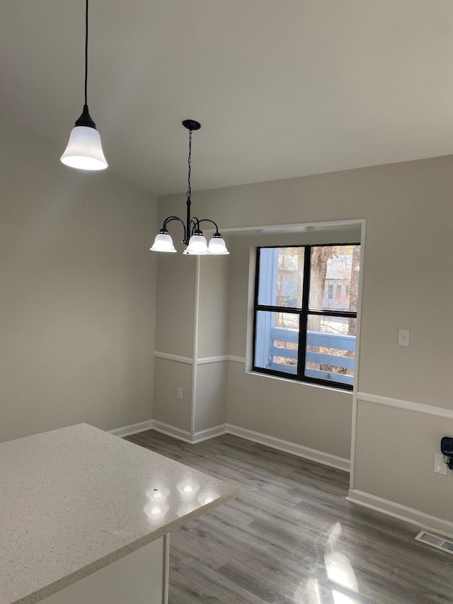 unfurnished dining area featuring hardwood / wood-style floors and an inviting chandelier