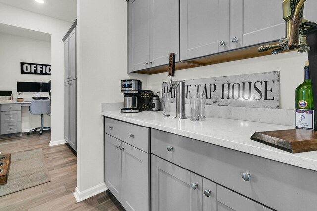 kitchen featuring gray cabinetry, light stone counters, and wood-type flooring