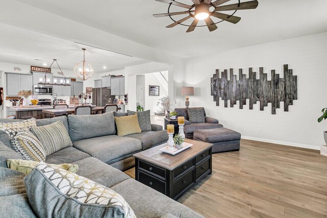 living room featuring light hardwood / wood-style floors and ceiling fan with notable chandelier