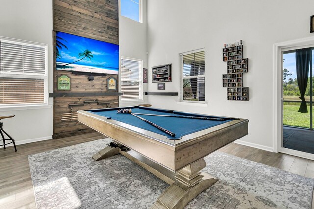 rec room with wood walls, hardwood / wood-style flooring, a high ceiling, and billiards