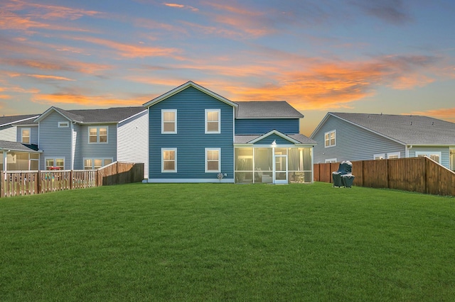 back of house featuring a yard, roof with shingles, a fenced backyard, and a sunroom