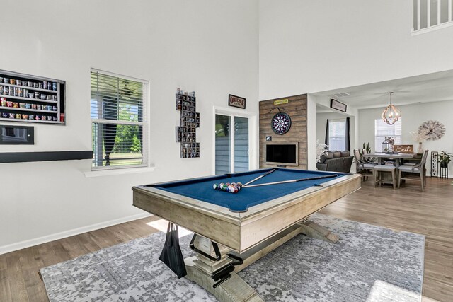 game room featuring hardwood / wood-style floors, pool table, a towering ceiling, and a notable chandelier