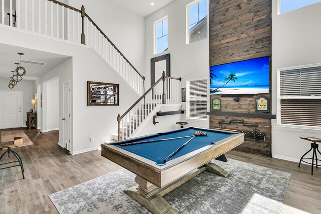 playroom with billiards, a healthy amount of sunlight, wood walls, hardwood / wood-style floors, and a high ceiling