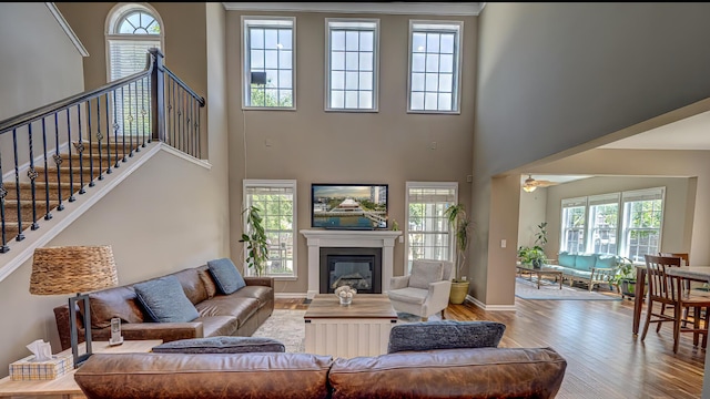 8009 Indian Hill Dr, Hanahan, SC 29410 - living room featuring stairs, a glass covered fireplace, a towering ceiling, wood finished floors, and baseboards