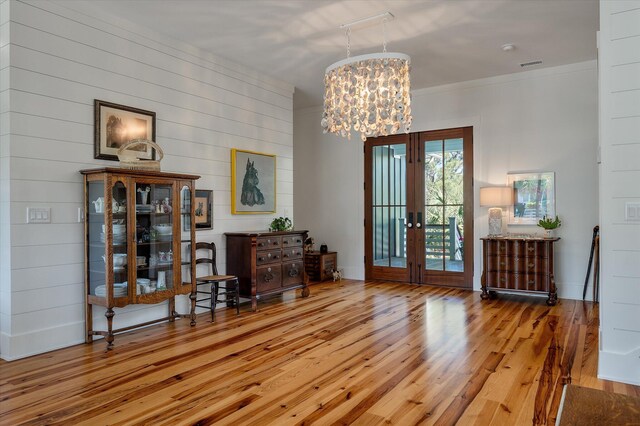 409 W Indian Ave, Folly Beach, SC 29439 - interior space with visible vents, wood walls, a chandelier, hardwood / wood-style flooring, and french doors