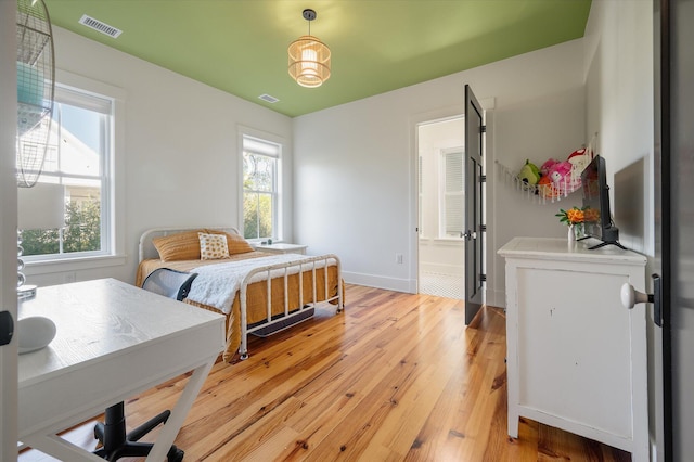 409 W Indian Ave, Folly Beach, SC 29439 - bedroom with visible vents, baseboards, light wood finished floors, and multiple windows