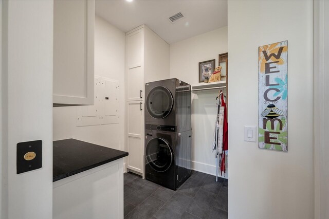 409 W Indian Ave, Folly Beach, SC 29439 - laundry room featuring visible vents, electric panel, stacked washer and dryer, cabinet space, and dark tile patterned flooring