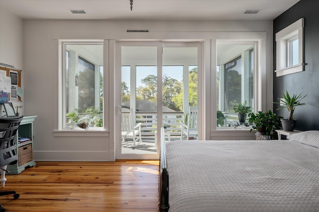 409 W Indian Ave, Folly Beach, SC 29439 - bedroom with access to outside, multiple windows, visible vents, and wood finished floors