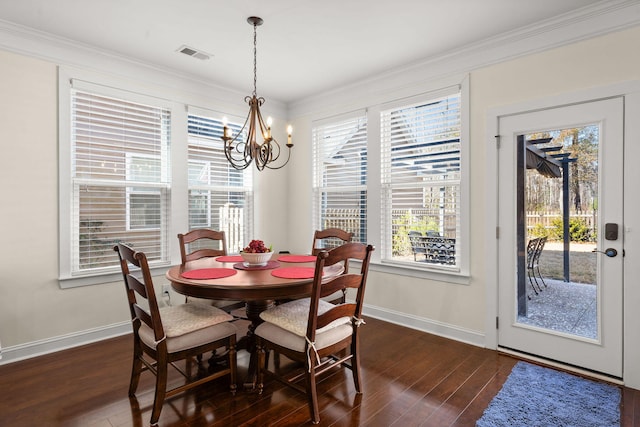 dining area with ornamental molding, a healthy amount of sunlight, dark wood-type flooring, and a chandelier